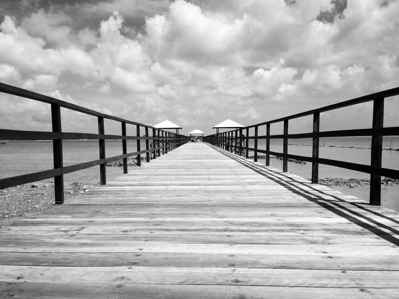 the way forward, railing, sky, diminishing perspective, pier, built structure, cloud - sky, boardwalk, water, wood - material, long, vanishing point, footbridge, sea, connection, architecture, cloud, tranquility, cloudy, wood