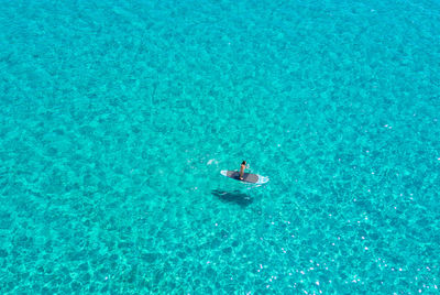 High angle view of woman paddleboarding on sea during sunny day