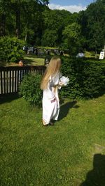 Girl wearing white dress standing on grassy field