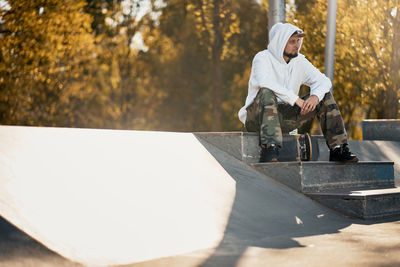 Full length of man with skateboard sitting on steps