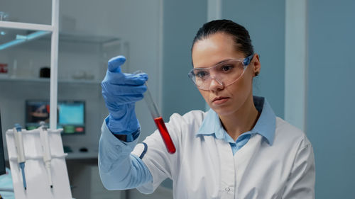 Portrait of doctor holding dentures while standing in laboratory