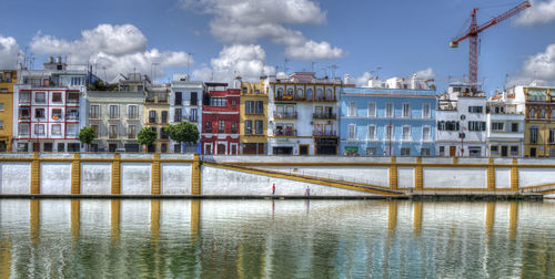 Buildings by river against sky in city