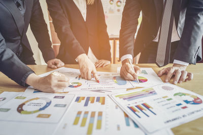 Business people working over graphs on table at office