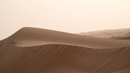 Sand dunes in desert against clear sky