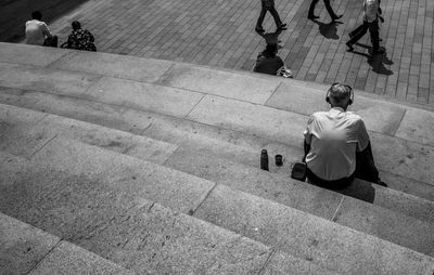 View of man listening music while sitting on staircase