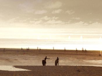 Silhouette people on beach against sky