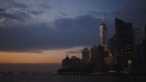 Illuminated buildings in city against sky at dusk