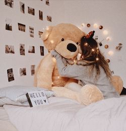 Woman hugging teddy bear on bed at home