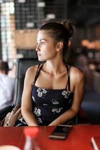 Young woman looking away while sitting in restaurant