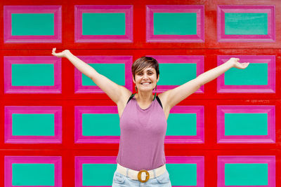 Portrait of young woman standing against wall