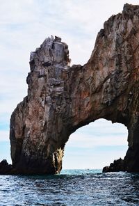 Rock formation by sea against sky