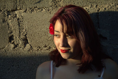 Close-up of young woman looking away by wall