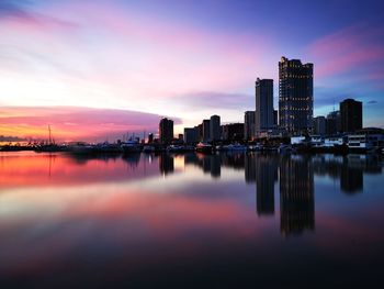 Scenic view of river by buildings against sky during sunset