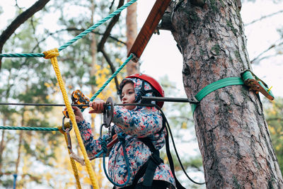 Low angle view of woman standing by tree trunk