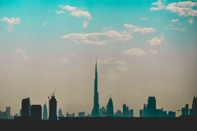 Skyscrapers in city against cloudy sky