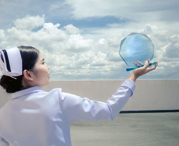 Nurse holding shield against cloudy sky