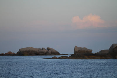 Rocks by sea against sky during sunset