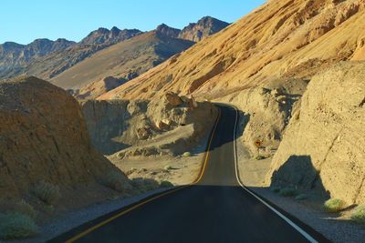 Road leading towards mountains against sky