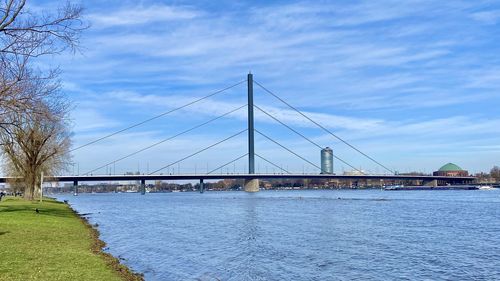 Bridge over calm river against cloudy sky