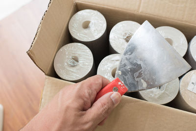 Cropped hand holding equipment on cardboard box at table