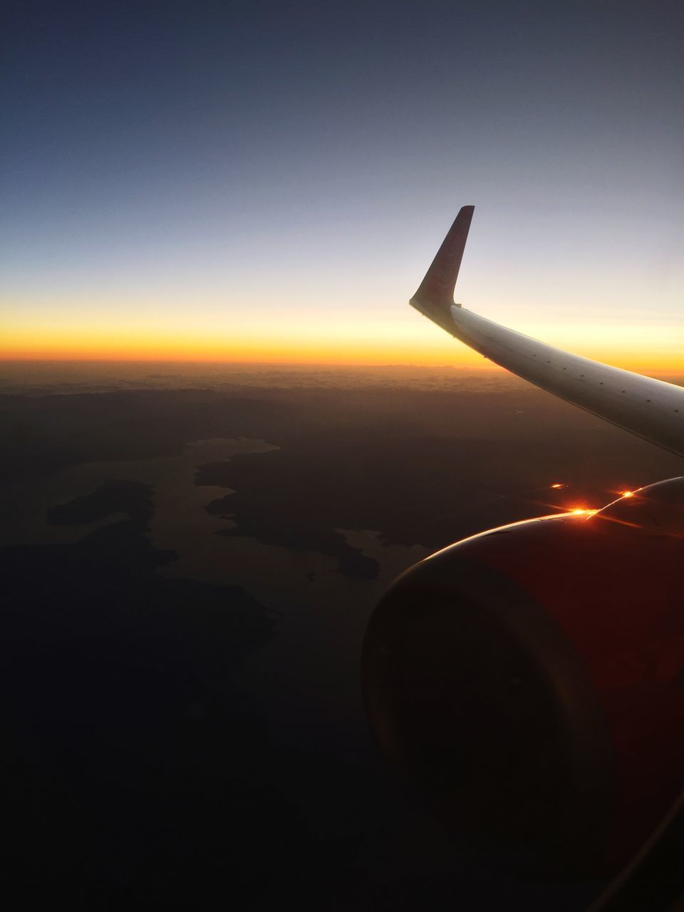 AIRPLANE WING OVER SEA AGAINST SKY