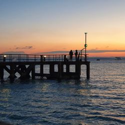 Silhouette pier over sea against sky during sunset