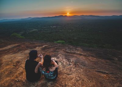 Couple sitting on mountain during sunset