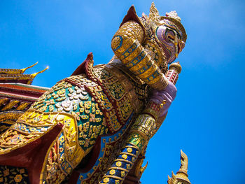 Low angle view of statue against temple building against clear blue sky