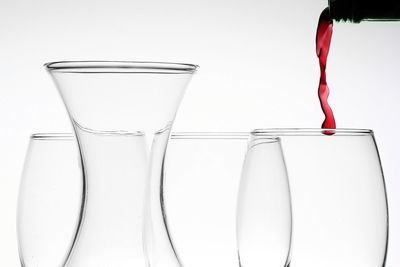 Close-up of wineglass on glass against white background