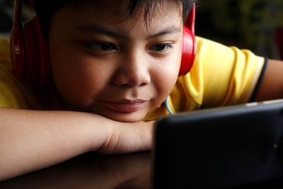 Close-up of boy using phone while listening music at home