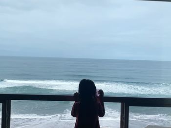 Rear view of woman photographing sea against sky