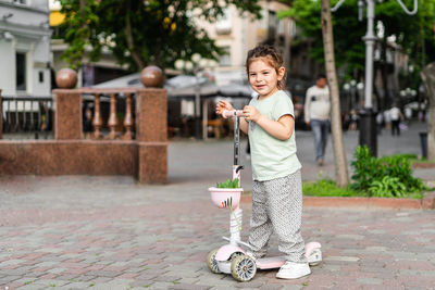 Portrait of girls standing on push scooter