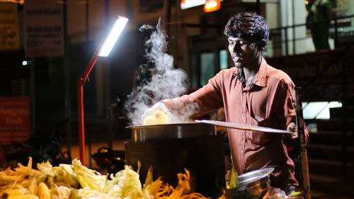Vendor with corns by market stall at night