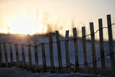 Wooden fence on field against sky during sunset