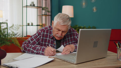 Man using laptop while sitting on table