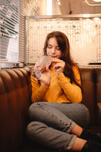 Teenage girl enjoying chocolate milkshake while sitting in cafe