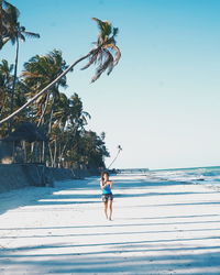 Woman walking on beach against clear sky