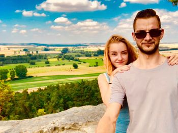 Portrait of young couple wearing sunglasses against landscape