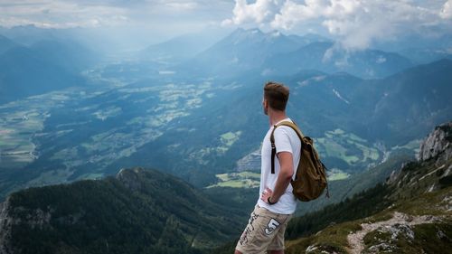 Rear view of woman standing on mountain against sky