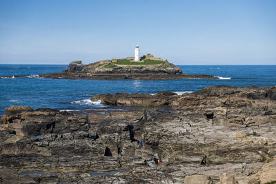 Lighthouse by sea against sky