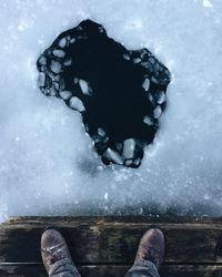 Low section of person standing on snow covered landscape