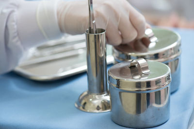 Cropped hand of doctor holding container on table