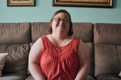 Adult woman with down syndrome smiles and looks at camera at home