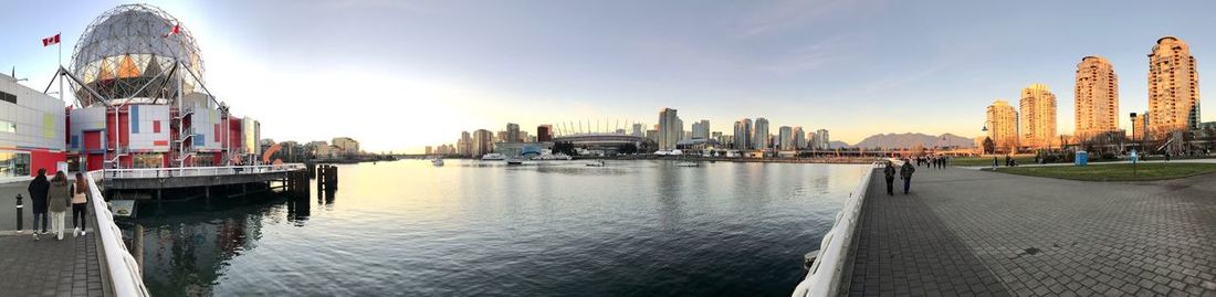 Panoramic view of buildings by river against sky in city