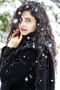 Portrait of beautiful woman standing during snowfall