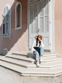 Full length of woman sitting on staircase against building