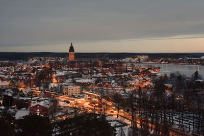 Aerial view of snow covered cityscape against cloudy sky during sunset