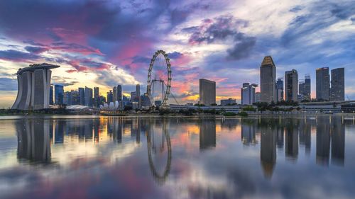 Reflection of buildings in lake against sky during sunset