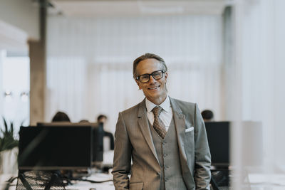 Portrait of smiling mature businessman wearing eyeglasses standing in office