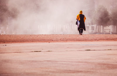 Rear view of woman walking on field in city